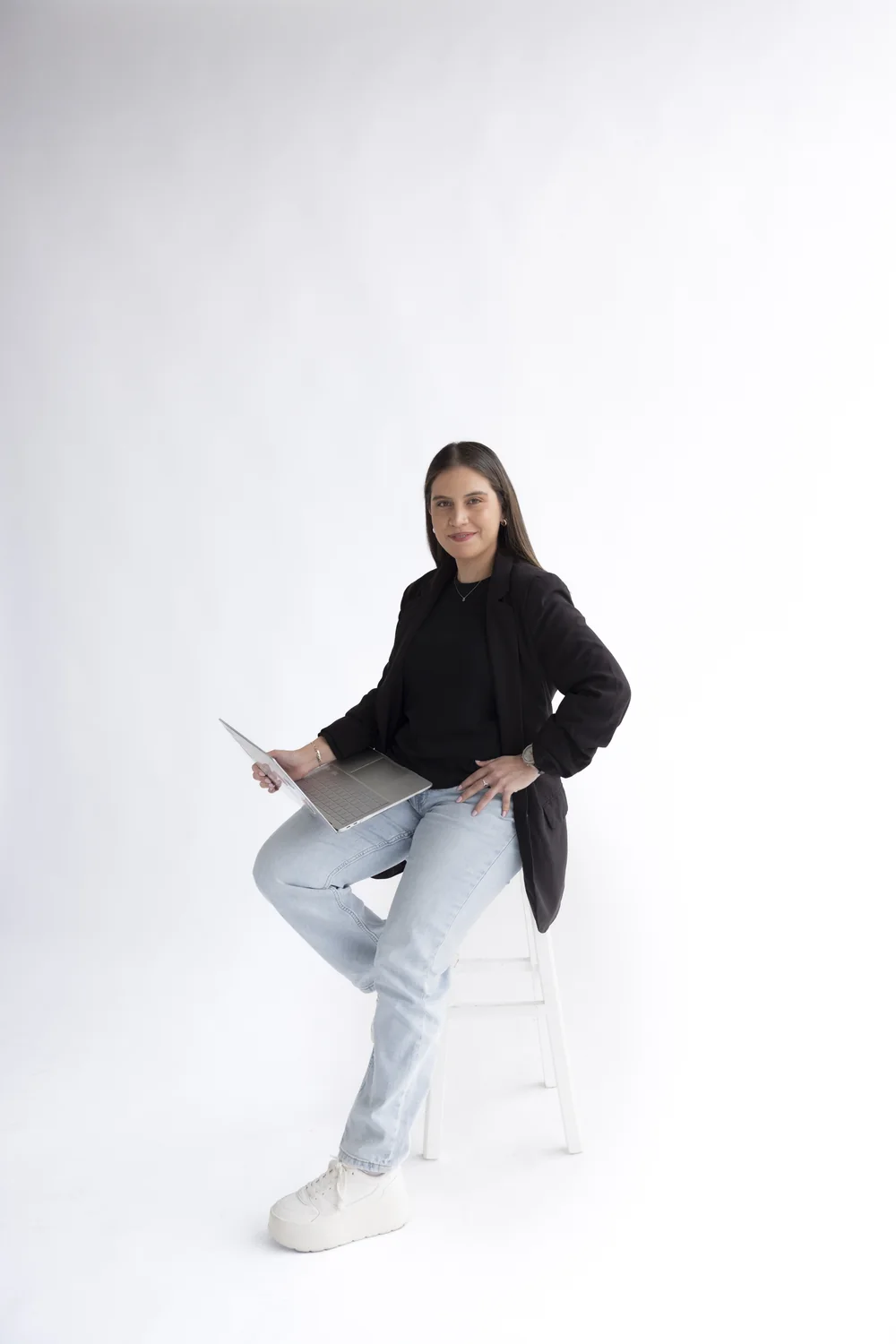 Bárbara Reyes sentada en un taburete con una laptop, lista para una consulta